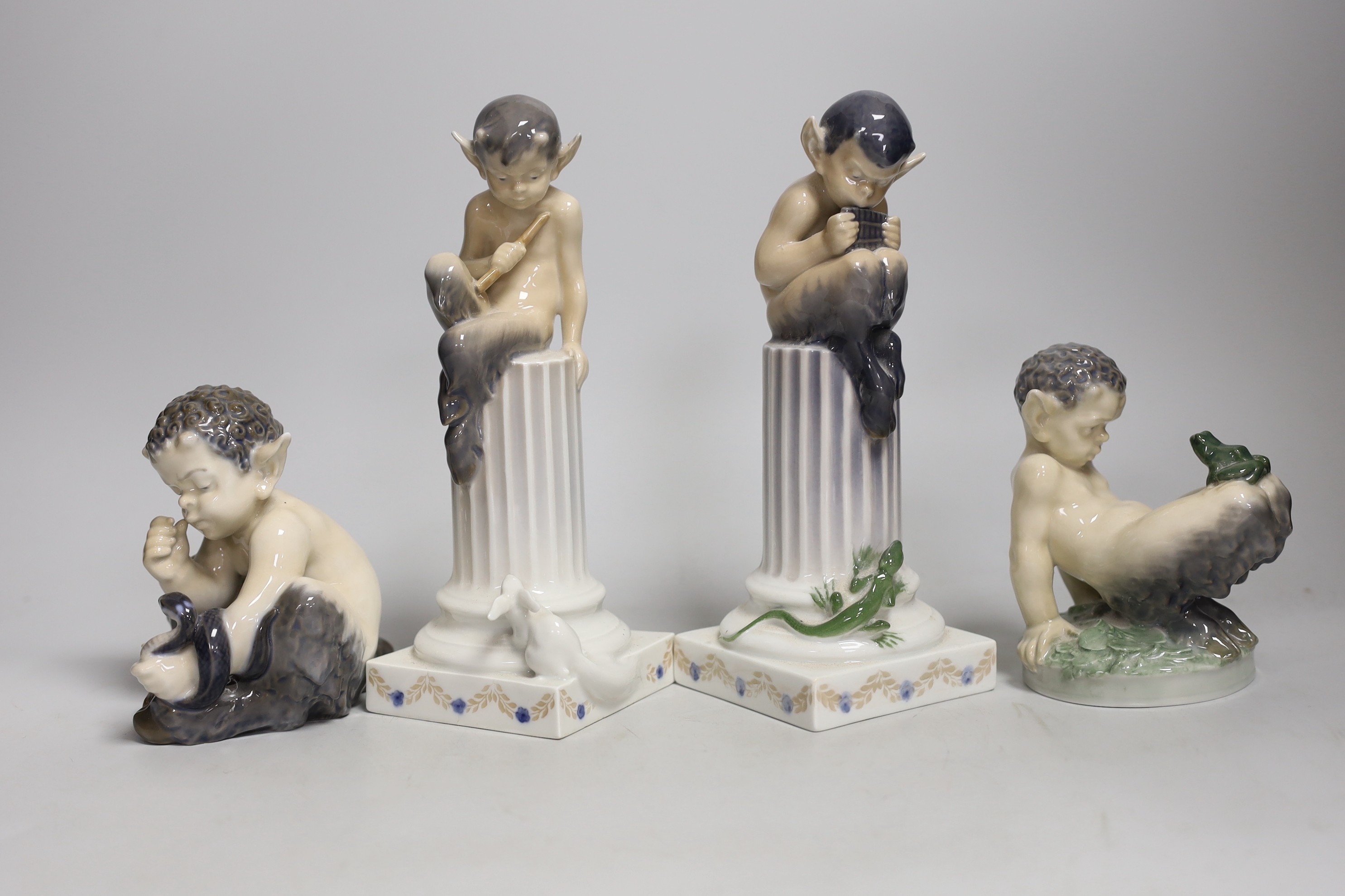 Four Royal Copenhagen models of Fauns, two playing musical instruments, one with a snake, the other with a frog. Tallest 21cm